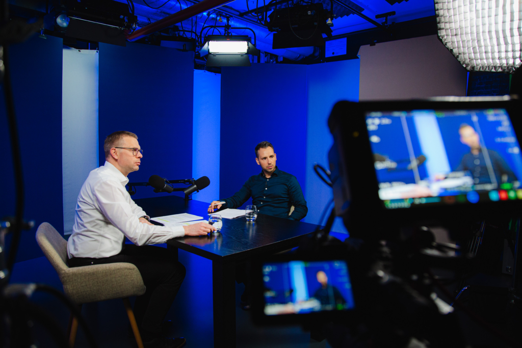 Das Bild zeigt Maximilian Kreitlmeier (Teamleiter Portfoliomanagement und Analyse, Fonds Finanz) und Daniel Arndt (Leiter Investment, Fonds Finanz) an einem Tisch sitzend mit Mikrofonen, wie sie den Videopodcast aufzeichnen.